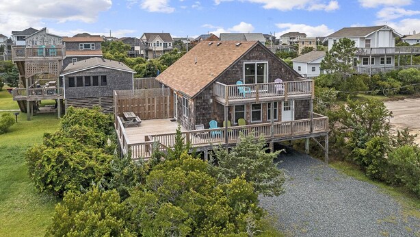 A coastal house with a deck, a covered porch, and a small outdoor seating area. - Semi oceanfront home in Salvo w/ beach access just across the street! (Salvo)