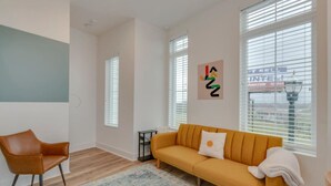 A modern living room with a yellow sofa, a brown leather chair, and a patterned rug.