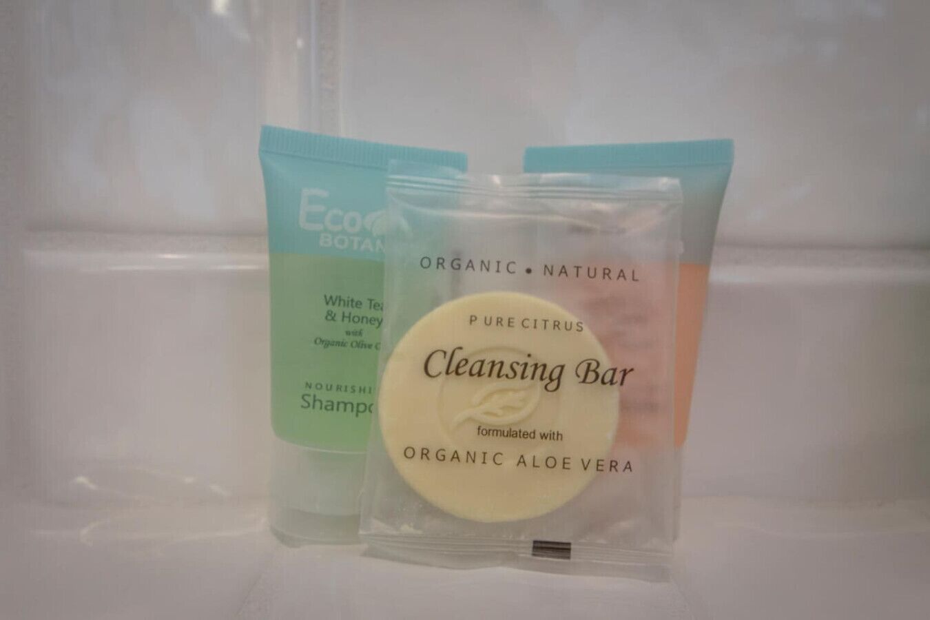 Deux bouteilles de shampooing Eco Botanics au thé blanc et au miel, et un savon purifiant à l’extrait d’agrumes.
