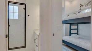 A room with a bunk bed, a shower area, and a small cabinet.