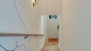 A staircase with a wooden handrail and a white wall with abstract line drawings.