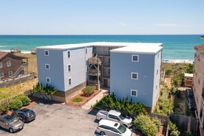 Un bâtiment à deux étages, doté d’un toit plat, d’un escalier central et d’un espace de stationnement où sont garées des voitures.