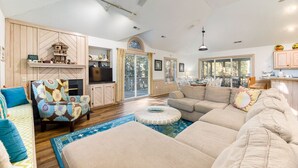 Un salon spacieux avec un grand canapé, un fauteuil à motifs et un téléviseur.