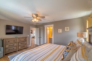 Relax in this inviting bedroom with a large bed, flat-screen TV, and wooden dresser.