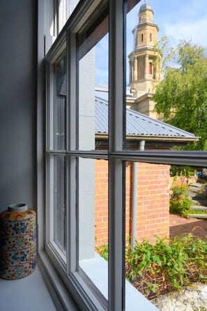 A window with a view of a brick building and a tower.