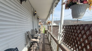 Un espace extérieur abrité, doté d’une terrasse en bois, de bancs en métal et d’une rambarde.