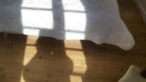 Ein Schlafzimmer mit einem hölzernen Bett, zwei Nachttischen mit Lampen, einem kleinen Stuhl und einem Holzboden.