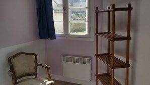 Ein Zimmer mit Holzstuhl, Fenster mit Blick, Heizkörper und einer Holzablage.
