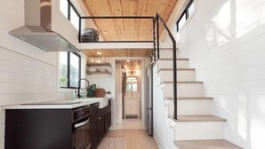 Una cucina stretta con isola nera, soffitto in legno e pareti bianche.