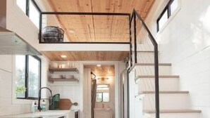 Una cucina moderna con travi in legno a soffitto, un'isola centrale e una scala che conduce a un livello superiore.