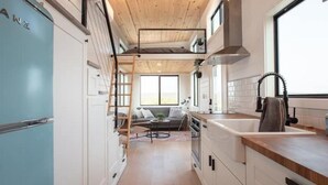 Une cuisine compacte équipée d’une cuisinière intégrée, d’un évier et d’une fenêtre donnant sur l’intérieur.