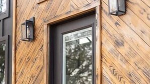 Un bâtiment moderne avec une façade en bois et une porte de couleur sombre.