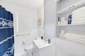 Un baño con lavamanos, inodoro y cortina de ducha blancos.
