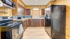 A kitchen with wooden cabinets, a stainless steel refrigerator, a microwave, and a stove. - Workers Haven - Pet Friendly- Patio - Fiber Wi-Fi - King Bed (Beaumont)
