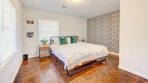 A bedroom with a bed, bedside table, and a window with blinds. - Workers Haven - Pet Friendly- Patio - Fiber Wi-Fi - King Bed (Beaumont)