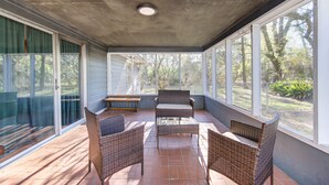 A covered patio with wicker furniture, a bench, and large windows offering views of the outdoors. - Workers Haven - Pet Friendly- Patio - Fiber Wi-Fi - King Bed (Beaumont)