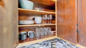 A wooden cabinet with shelves containing dishes, glasses, and mugs. - Workers Haven - Pet Friendly- Patio - Fiber Wi-Fi - King Bed (Beaumont)