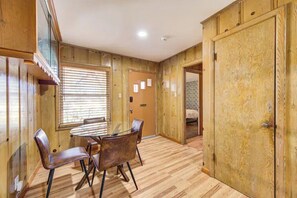 Una habitación con piso de madera, una mesa de vidrio con sillas y una puerta con diseño decorativo.