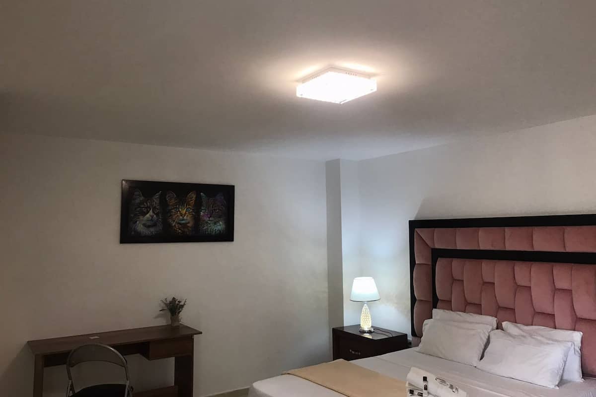 Ein Hotelzimmer mit Bett, Nachttisch, Lampe und einem Gemälde an der Wand.