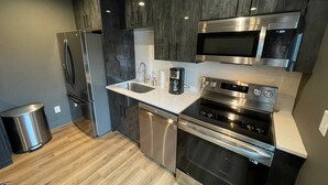 Una cocina moderna con electrodomésticos de acero inoxidable, lavavajillas y microondas.