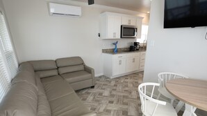 Una cocina moderna con gabinetes blancos, microondas integrado y cafetera.