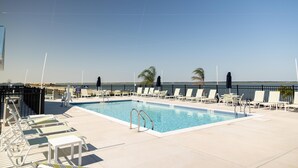 A pool area with lounge chairs and a clear view of the ocean.