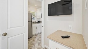 A modern kitchen with white cabinetry, a stainless steel refrigerator, and a beige countertop.