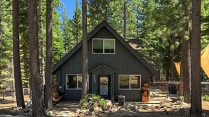A cabin with a dark exterior, large windows, and a front door.