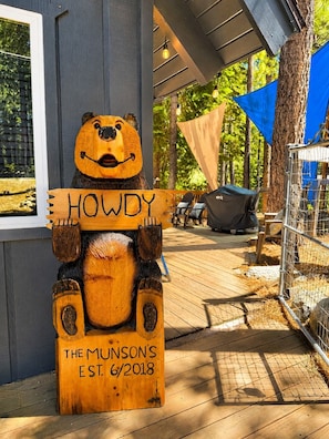 A wooden sign with a bear figure holding a sign that reads 'HOWDY' and 'THE MUNSON'S EST. 6/2018'.