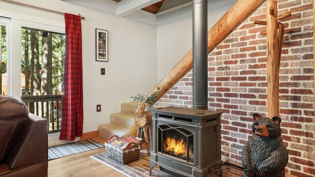 A cozy living room with a fireplace, a wooden staircase, and a bear statue.