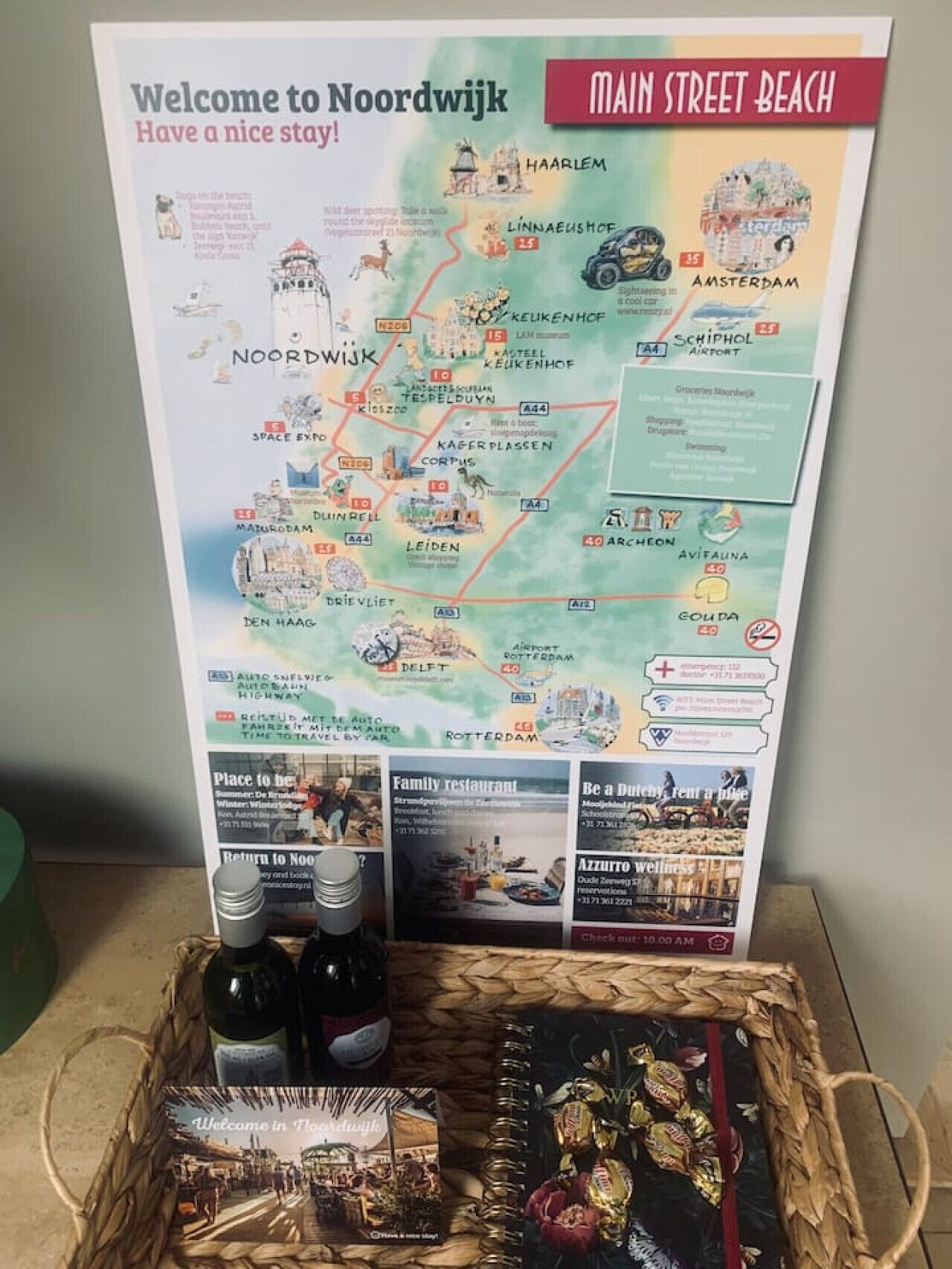 A welcome poster for Noordwijk with a map, travel information, and a basket with snacks and a bottle.