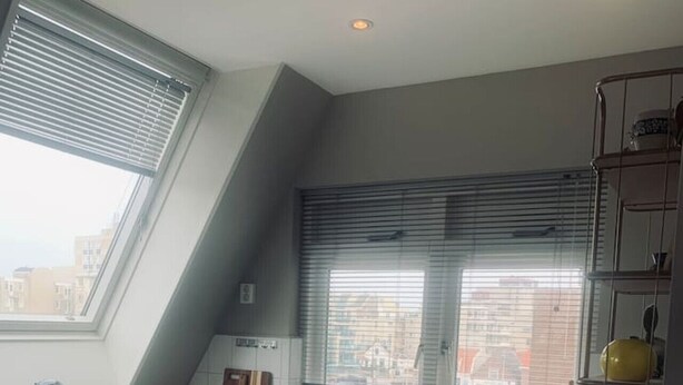 A modern kitchen with a large window, a built-in oven, and a countertop with a kettle and a coffee maker. - Main Street Beach apartment 150 meters from the beach  (Noordwijk)