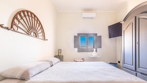 Un dormitorio con cama, televisor montado en la pared, armario y aire acondicionado.