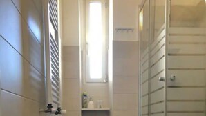 Une salle de bain équipée de toilettes, d’un bidet et d’une douche à parois de verre.