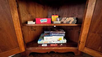 A wooden cabinet with two shelves, each holding various board games.