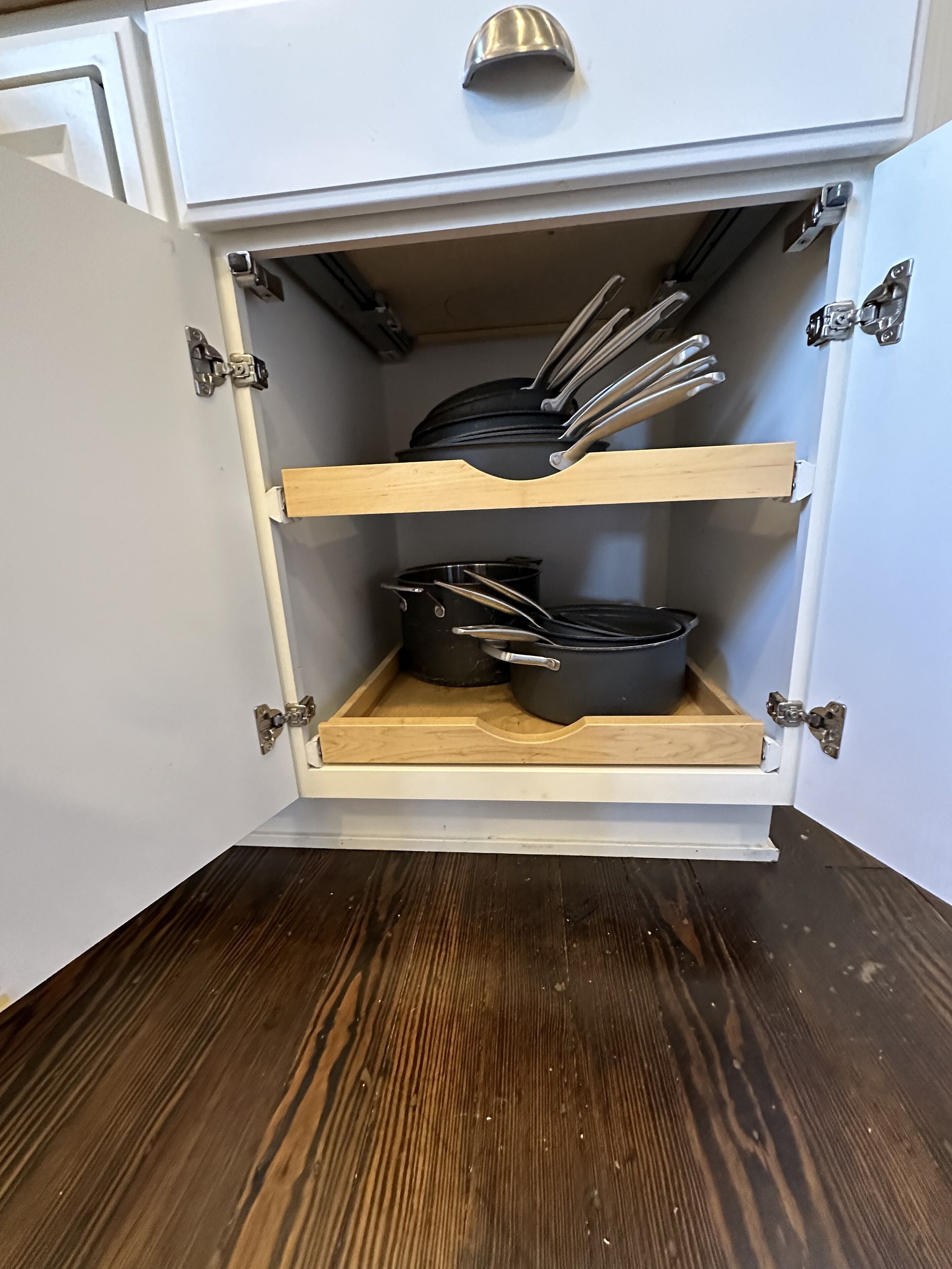 A kitchen cabinet with two shelves, each holding pots and pans.