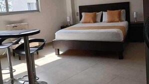 A modern hotel room with a bed, a dining table, and a window. - 506 Moderno Aparta-Suite en Versalles Tipo Loft - Cali Tower Suites & Lofts (Cali)