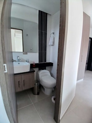 A modern bathroom with a white toilet, a sink, and a mirror. - 506 Moderno Aparta-Suite en Versalles Tipo Loft - Cali Tower Suites & Lofts (Cali)