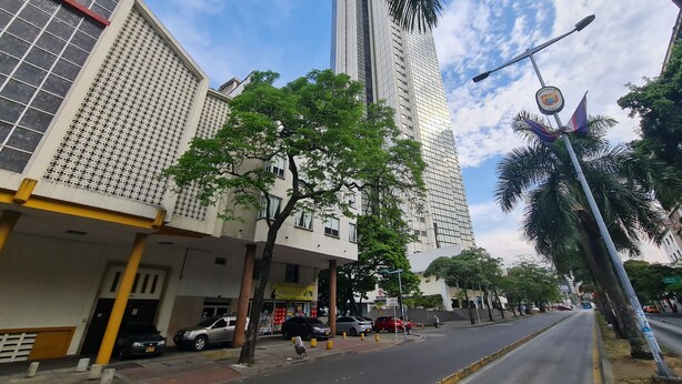 A street view with tall buildings, parked cars, and a clear sky. - 506 Moderno Aparta-Suite en Versalles Tipo Loft - Cali Tower Suites & Lofts (Cali)
