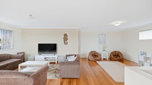 Een moderne woonkamer met een flatscreen televisie, twee bruine leren fauteuils, een witte salontafel en een bruine bank.