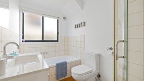 Een moderne badkamer met een bad, toilet en wastafel.