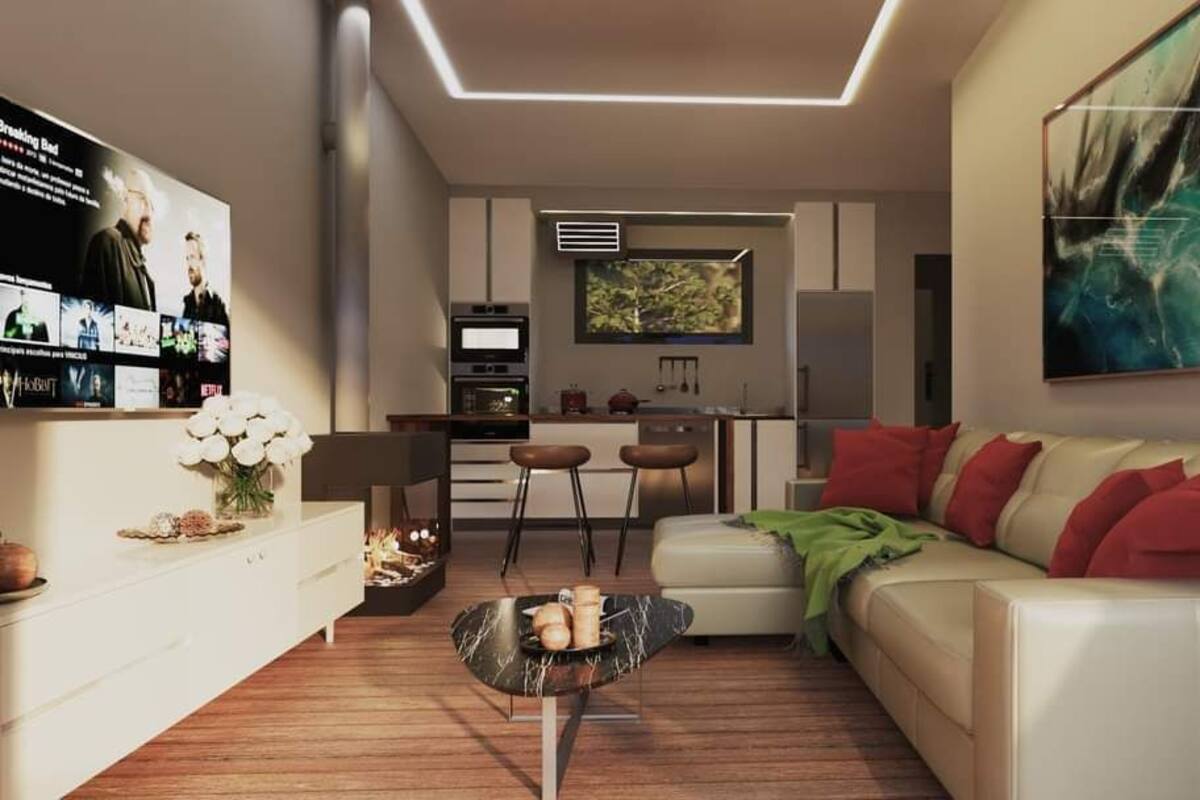 Un salon moderne avec un canapé blanc, une table basse et un téléviseur diffusant un film. On y trouve également un coin cuisine avec une table à manger et des chaises.