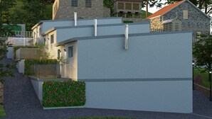 Een modern gebouw met een plat dak, een gevel van natuursteen en een kleine tuin met rode bloemen.