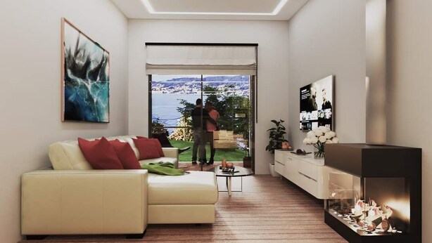 Een moderne woonkamer met een bank, een open haard en uitzicht op zee.
