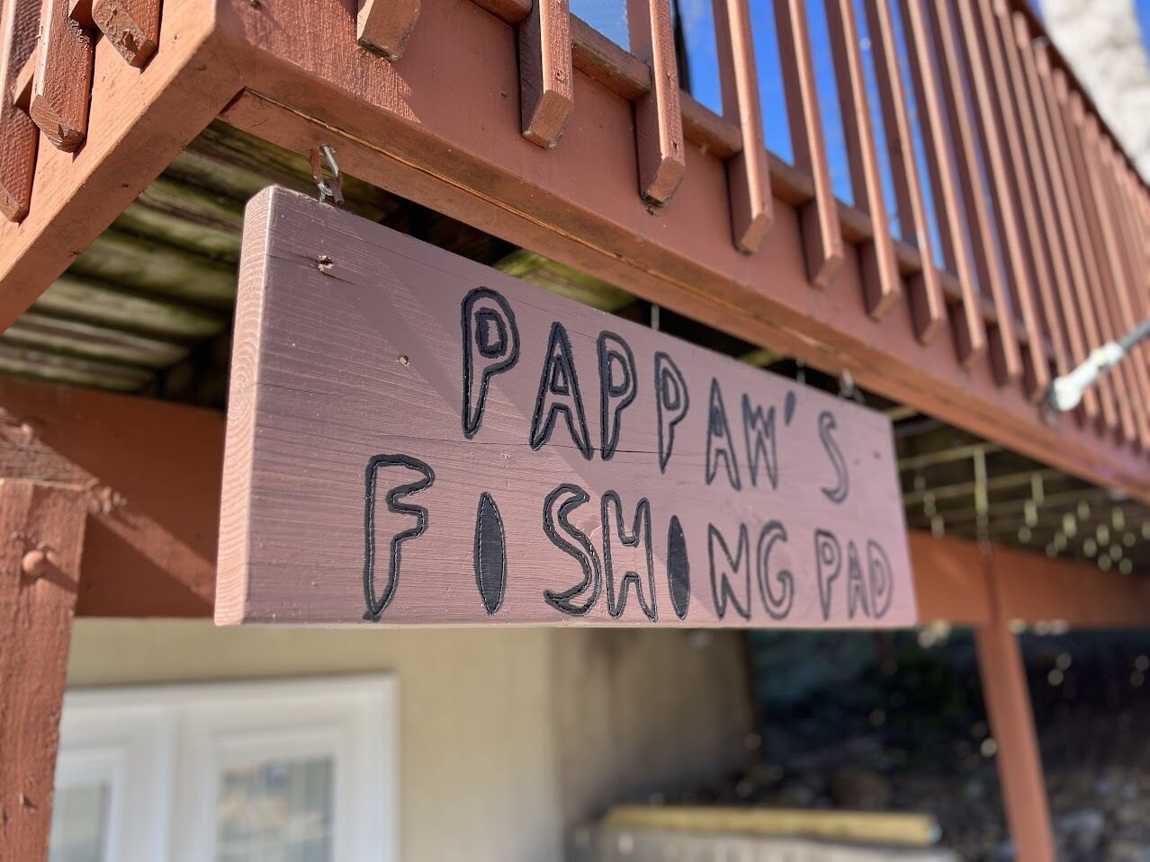 Un cartello di legno con la scritta "PAPPAN'S FISHING PAD" appeso a una struttura.