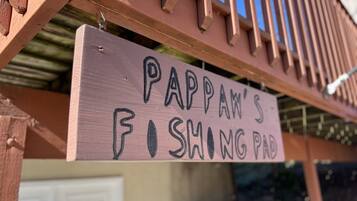 Un cartello di legno con la scritta "PAPPAN'S FISHING PAD" appeso a una struttura.