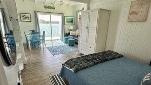 A room with a bed, a desk, a chair, a wardrobe, and a view of the sea.