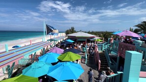 A beachside walkway with colorful umbrellas and a crowd of people.