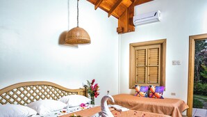 Una habitación con dos camas, cabeceros de madera, ventilador de techo, equipo de aire acondicionado y una ventana con persianas de madera.
