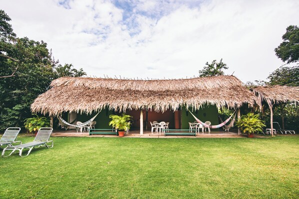 A thatched-roof structure with outdoor seating and potted plants.
